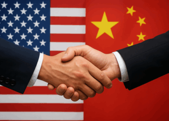 Imagen realista horizontal que muestra un apretón de manos en primer plano, simbolizando cooperación y diplomacia. En el fondo aparecen las banderas de Estados Unidos y China, representando un encuentro bilateral o acuerdo internacional entre ambas potencias.