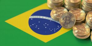 Monedas físicas de bitcoin doradas sobre la parte superior derecha de la bandera de Brasil.