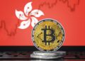 Una moneda fisica de bitcoin y la bandera de Hong Kong.