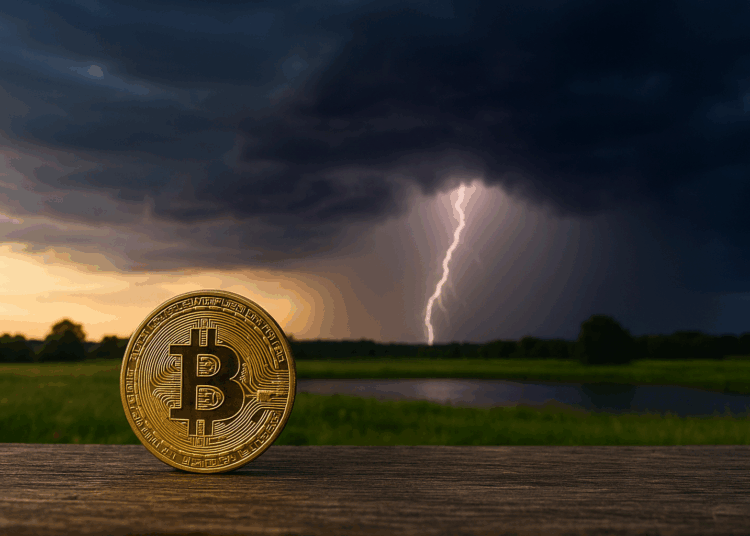 Moneda de Bitcoin en primer plano sobre una superficie de madera, brillando con tonos dorados. El entorno se muestra tranquilo, con un campo verde y un lago detrás. Al fondo, una tormenta comienza a formarse con nubes oscuras y un rayo iluminando el cielo.