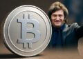 Imagen realista horizontal que muestra una gran moneda plateada de Bitcoin en primer plano, con el presidente de Argentina, Javier Milei, sonriendo y saludando triunfante en el fondo, vestido con traje oscuro.
