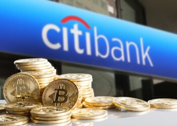 Fachada del edificio de Citibank con unas monedas de bitcoin doradas al frente.
