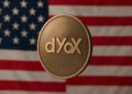 Moneda de dYdX en primer plano, con acabado metálico y de fondo, la bandera de Estados Unidos con sus franjas rojas y blancas y las estrellas sobre fondo azul.