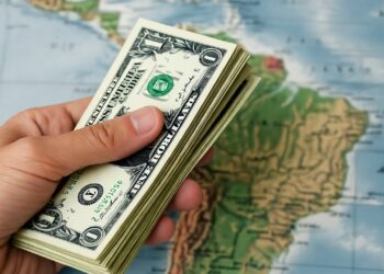 Dólares sostenidos por una mano con un fondo del continente americano.