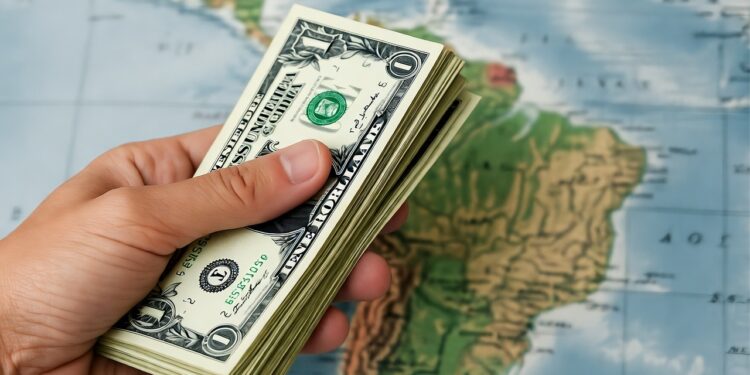 Dólares sostenidos por una mano con un fondo del continente americano.