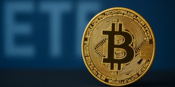 Moneda física de bitcoin dorada con las letras ETF de fondo.