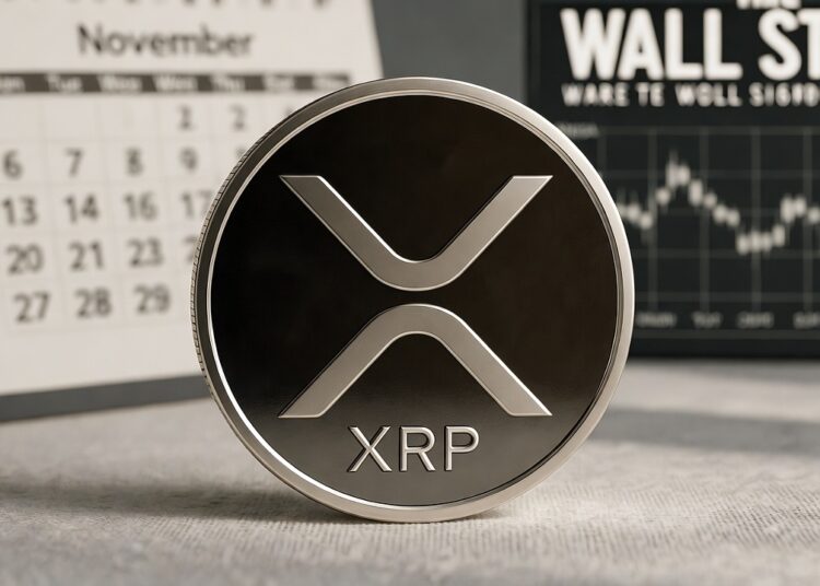 Una moneda física de XRP en primer plano, metálica con el logo blanco estilizado y la inscripción "XRP" grabada, reposa sobre una superficie de madera. En el fondo ligeramente desenfocado, un calendario de escritorio muestra el mes de noviembre y, a su lado, la señalización negra de "Wall Street".