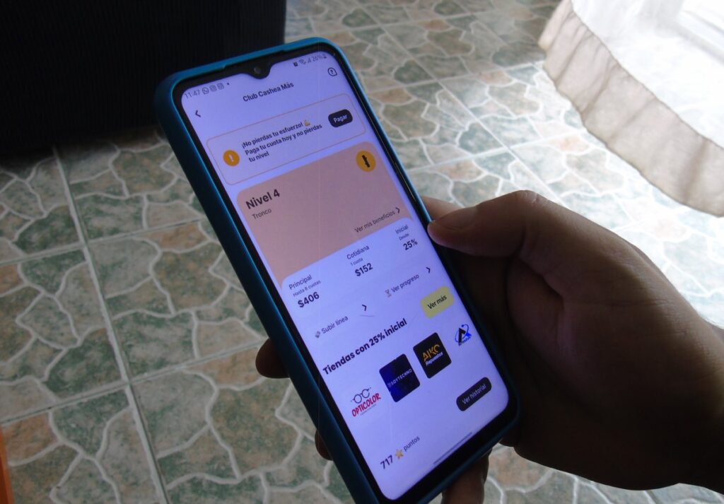 Fotografía de una mano sujetando un teléfono inteligente que muestra la interfaz de Cashea.