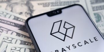 Logo de Grayscale en una pantalla de teléfono móvil sobre unos billetes de dólares.