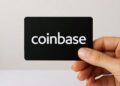 Una tarjeta negra con el nombre de Coinbase sostenida por una mano.