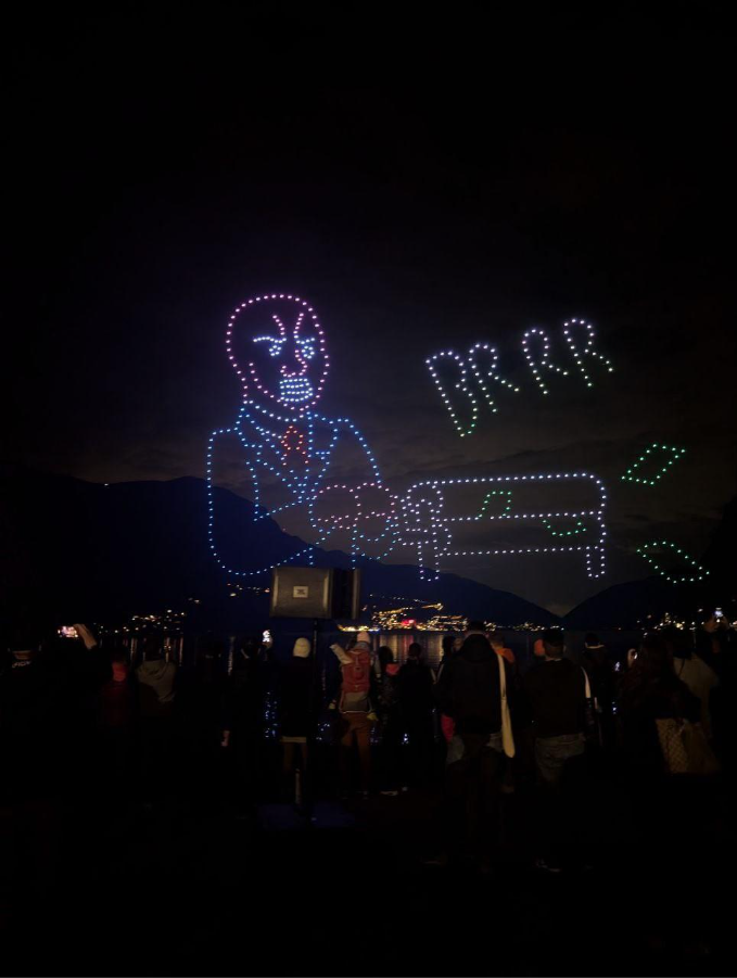 Night sky depicting a multi-colored image of a banker printing banknotes. below Lake Lugano.