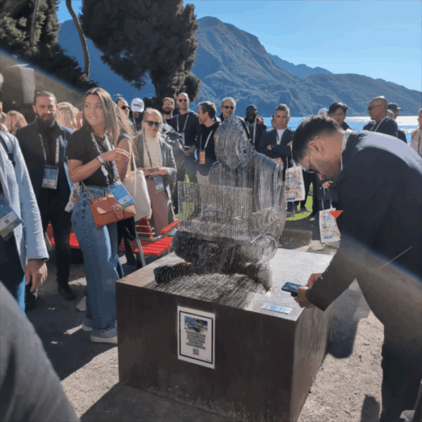 Un grupo de personas alrededor de una estatua de Satoshi Nakamoto que resalta en el centro.