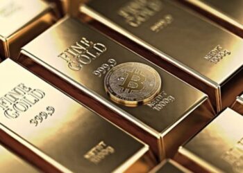 Lingotes de oro organizados con una moneda física de bitcoin dorada.