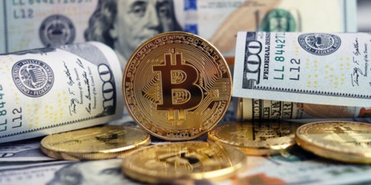Moneda física de bitcoin dorada rodeada de billetes de 100 dólares estadounidenses.