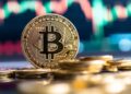 Moneda física de bitcoin dorada sobre un escritorio.