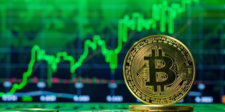 Moneda física de bitcoin dorada con gráficas verdes en el fondo.