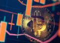 Moneda física de bitcoin dorada con velas de gráficos alrededor.