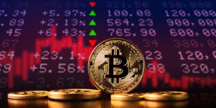 Monedas físicas de bitcoin doradas sobre un escritorio con una gráfica en rojo y números en el fondo.