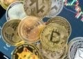 Monedas físicas de bitcoin, xrp, ethereum, doge, cardano, sobre una tablet.