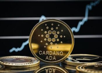 Moneda física de ADA en un escritorio, con fondo negro y una línea de gráfico en blanco.
