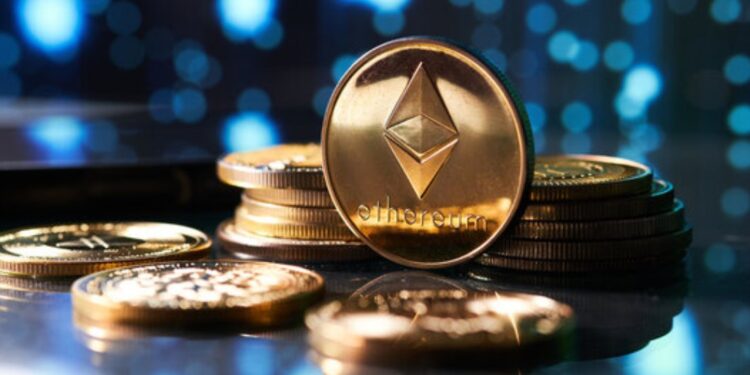 Moneda física dorada de ETH junto a otra sobre un escritorio.