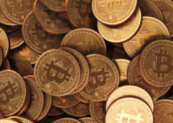 Monedas físicas de bitcoin doradas esparcidas en una mesa.