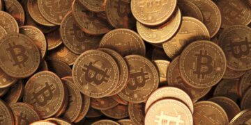 Monedas físicas de bitcoin doradas esparcidas en una mesa.