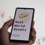 Un celular muestra en su pantalla las palabras Real World Assets.