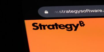 Logo de Strategy en la pantalla de un móvil con un fondo negro.