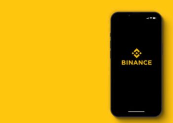 Teléfono inteligente que muestra el logo de Binance y un fondo amarillo.