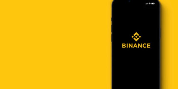 Teléfono inteligente que muestra el logo de Binance y un fondo amarillo.