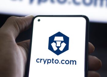 Mano sujetando un teléfono que muestra el logo de Crypto.com.