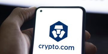 Mano sujetando un teléfono que muestra el logo de Crypto.com.