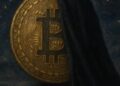 Una moneda de bitcoin tapada a la mitad por un velo oscuro en una noche estrellada.