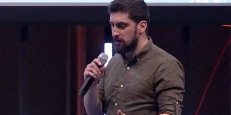 Amir Taaki en primer plano ofreciendo una conferencia sobre bitcoin.