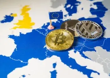 Monedas físicas con logos de criptomonedas arriba de un mapa europeo.