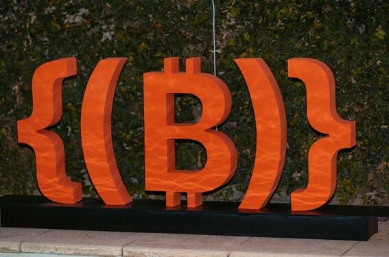 Nuevo logo deONG Bitcoin Argentina, símbolo de bitcoin en color naranja como decorativo en evento.