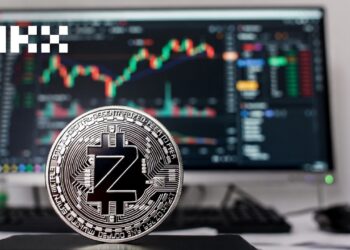 una moneda plateada de zcash, junto a una interfaz de trading en la pantalla de un computadora y el logo del exchange OKX.
