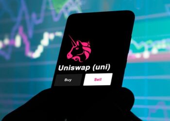 Un celular con el logo de Uniswap delante de gráfico de precios.