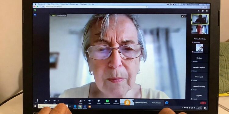 Una señora aparece en una llamada de Zoom recibiendo indicaciones para recuperar sus bitcoin.