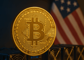 Moneda de Bitcoin en primer plano con equipos de minería y bandera de Estados Unidos al fondo