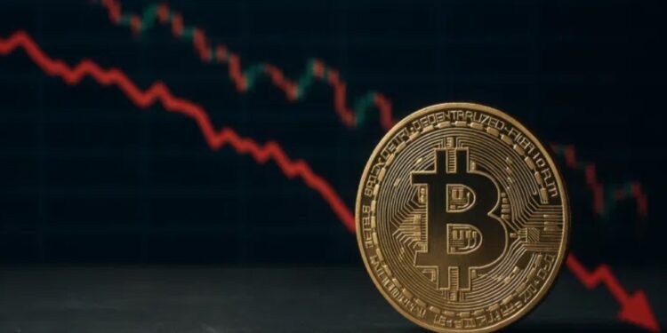 Una moneda física de bitcoin delante de un gráfico de precios.