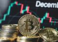 Monedas de bitcoin en primer plano y un gráfico de precio en el fondo con la leyenda "december".