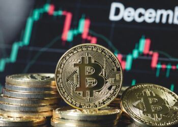 Monedas de bitcoin en primer plano y un gráfico de precio en el fondo con la leyenda "december".