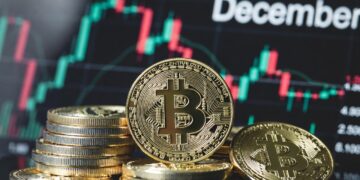 Monedas de bitcoin en primer plano y un gráfico de precio en el fondo con la leyenda "december".