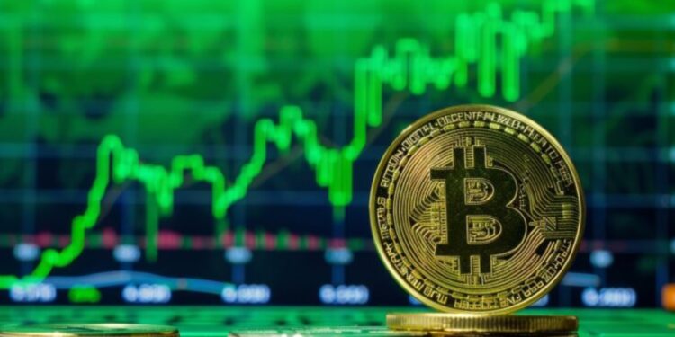 Moneda física de bitcoin dorada con gráficas verdes en el fondo.