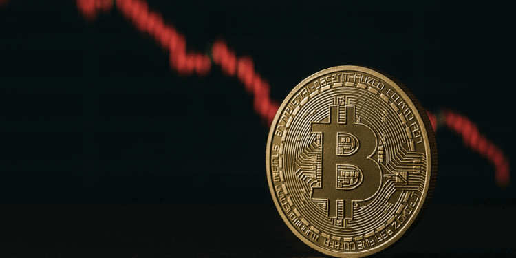 Moneda de bitcoin y gráfico de precio mostrando una caída.