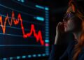 Mujer observa con preocupación una pantalla en la que se muestra un gráfico de velas rojas con fuerte tendencia bajista.