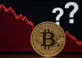 Moneda física de bitcoin dorada con gráficas rojas y signos de interrogación.