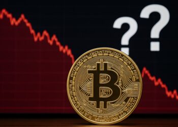 Moneda física de bitcoin dorada con gráficas rojas y signos de interrogación.